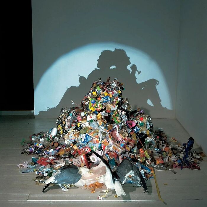 A pile of colorful trash creates a surreal shadow of a couple, embodying surrealism.