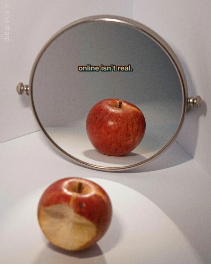 Surrealism-themed image showing a bitten apple reflecting as whole in a mirror with text “online isn't real.”