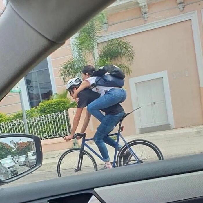 Two people in an unusual bike ride, with one sitting on the other's back, showcasing weird adorable moments for Instagram.