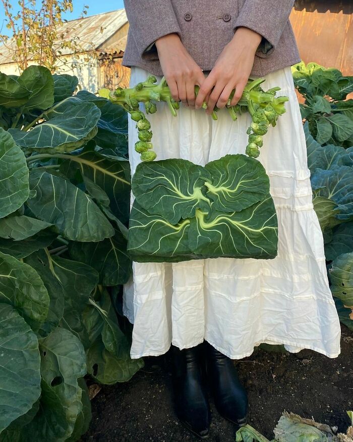 Person holding a surreal leaf handbag among large cabbage plants, showcasing surrealism art. 