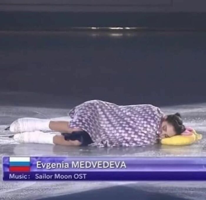 Figure skater wrapped in a blanket on the ice, performing to Sailor Moon OST, showcasing an adorable and weird moment.