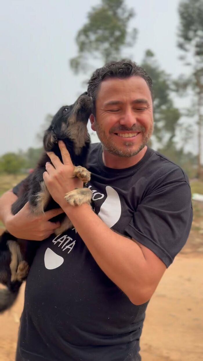 Man smiling while holding a stray dog, symbolizing 25 years of compassion and care for animals.