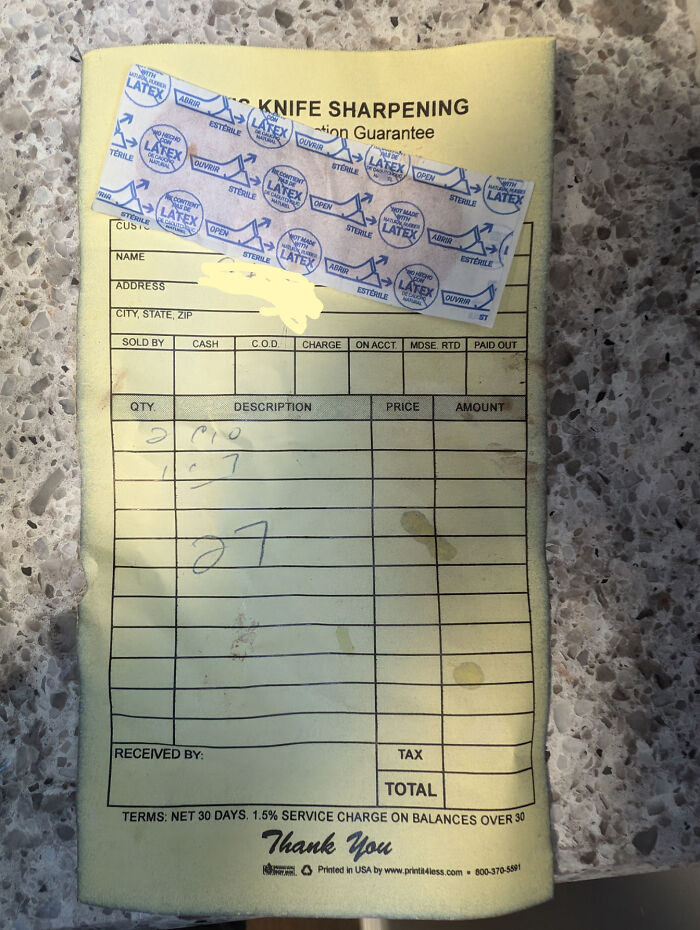 A mildly interesting used knife sharpening receipt with a latex bandage attached on a counter.