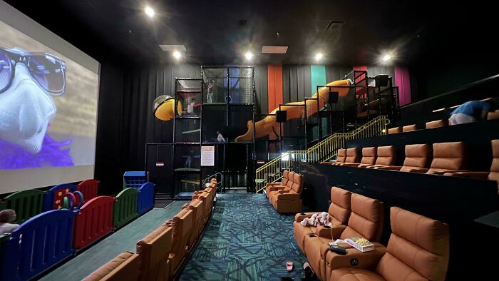 Movie theater with a play area beside seats, showing something mildly interesting on screen.