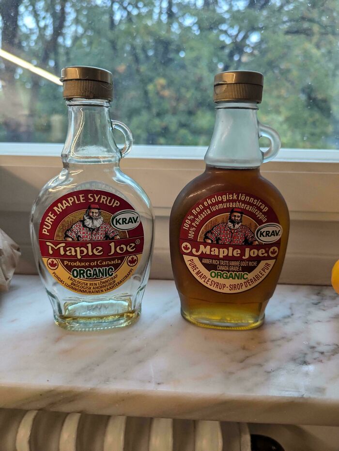 Two bottles of organic Maple Joe syrup on a windowsill, one empty and one full, showcasing mildly interesting contrast.