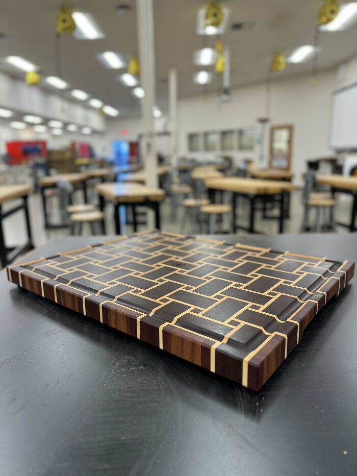 Woodworking project: a geometric patterned cutting board displayed in a workshop setting.