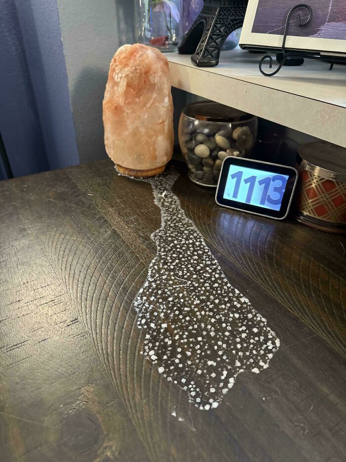 Salt lamp leaves a trail of salt residue on a wooden table, creating a mildly interesting pattern.