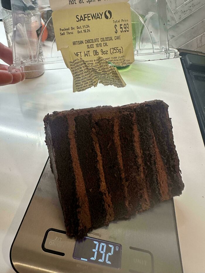 Chocolate cake slice labeled 0lb 9oz on a scale reading 392g, showcasing something mildly interesting.