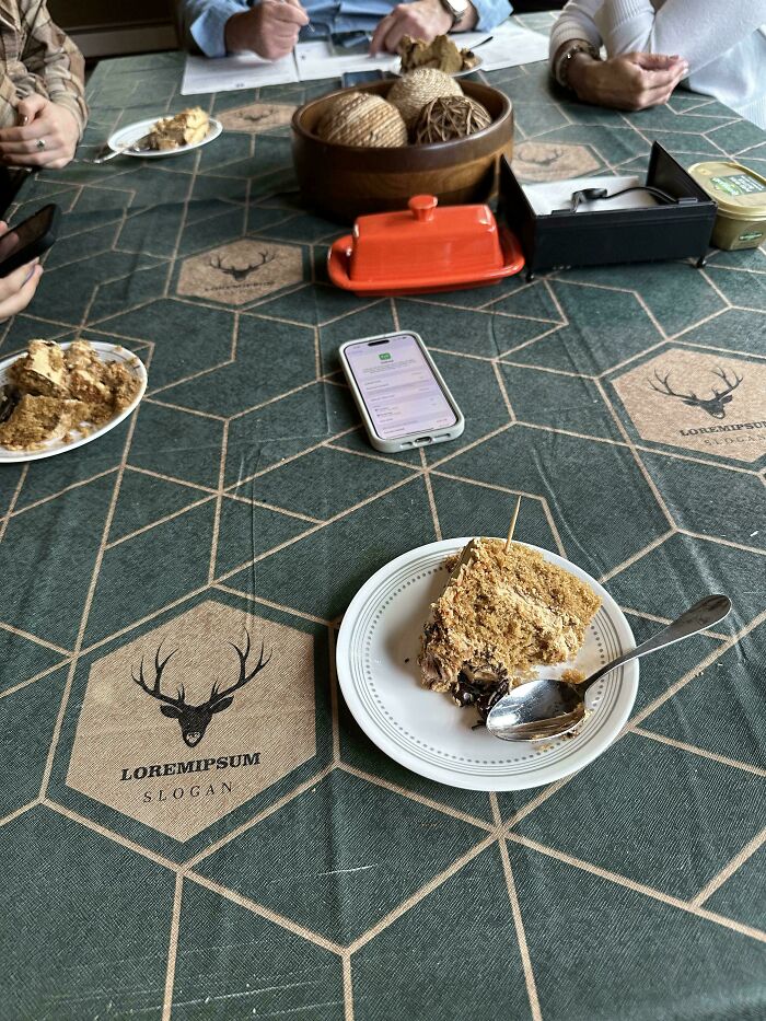 Mildly interesting table setup with desserts, a smartphone, and decorative balls on a geometric tablecloth.