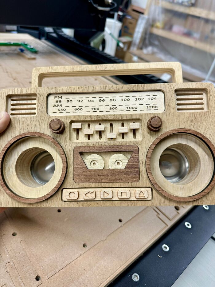 Woodworking project: intricately designed wooden boombox with detailed controls and speakers on a workspace.