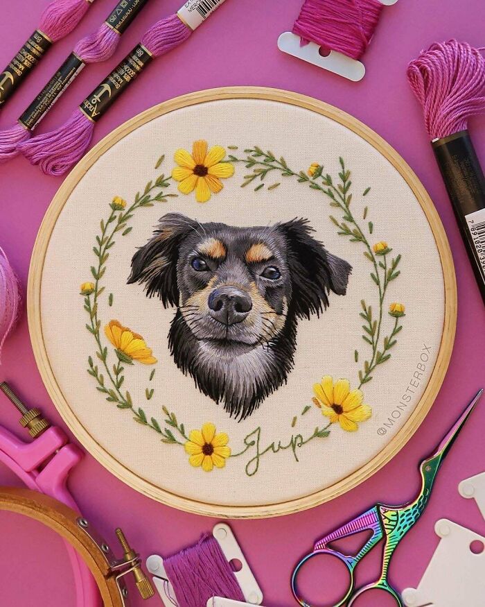 Creative dog embroidery with floral design surrounded by pink thread and scissors on a vibrant background.