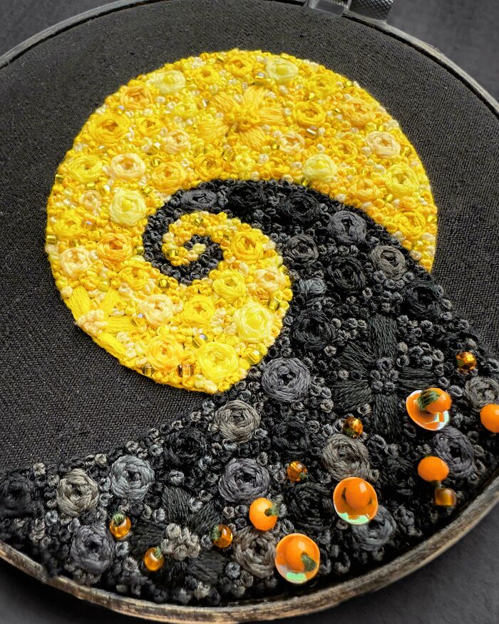 Creative embroidery of a swirling pattern with yellow and black threads on a hoop, showcasing artistic needlework.