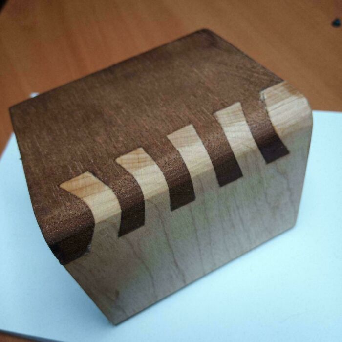 Woodworking project showcasing intricate dovetail joints on a wooden block.