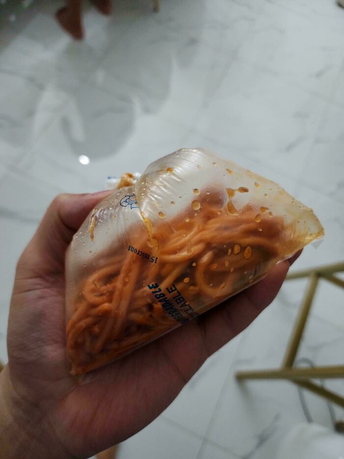 A hand holding a clear bag filled with spaghetti, showing something mildly interesting.