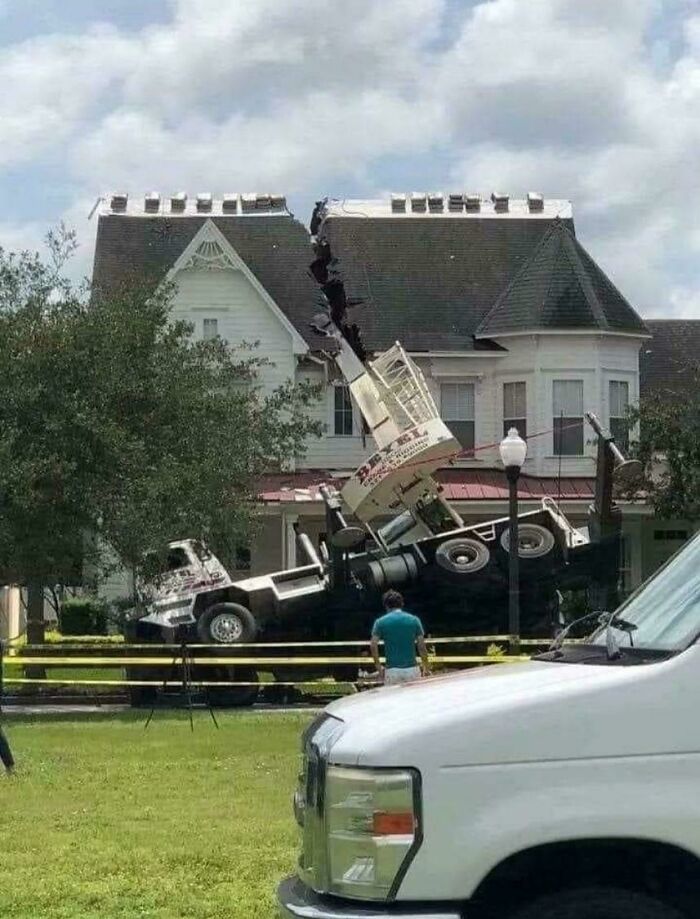 Crane truck toppled onto a house, causing a severe accident and potentially expensive damage.