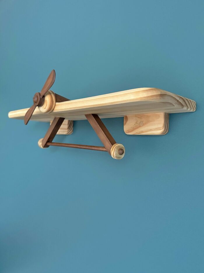 Woodworking project featuring a wooden airplane shelf mounted on a blue wall.