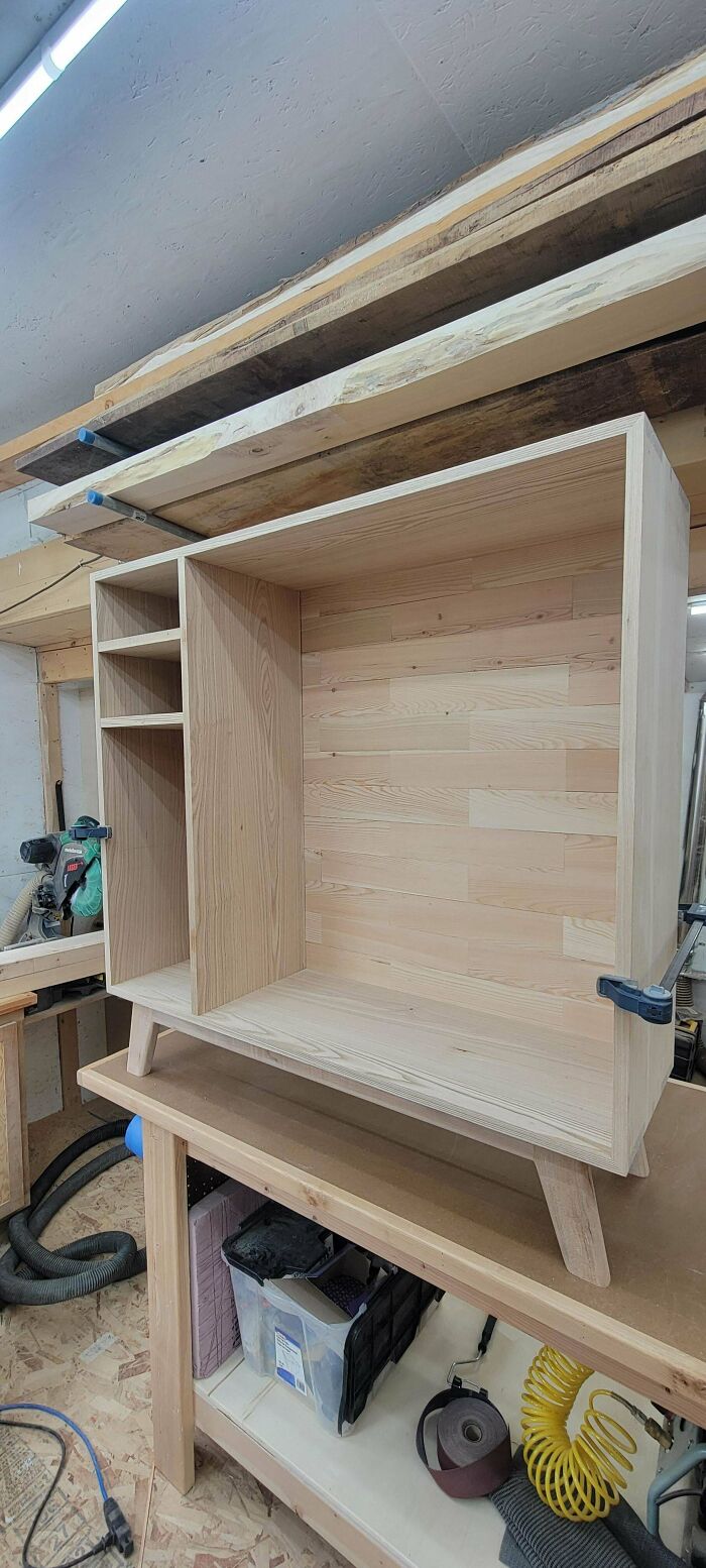 Woodworking project: a wooden cabinet under construction in a workshop setting.