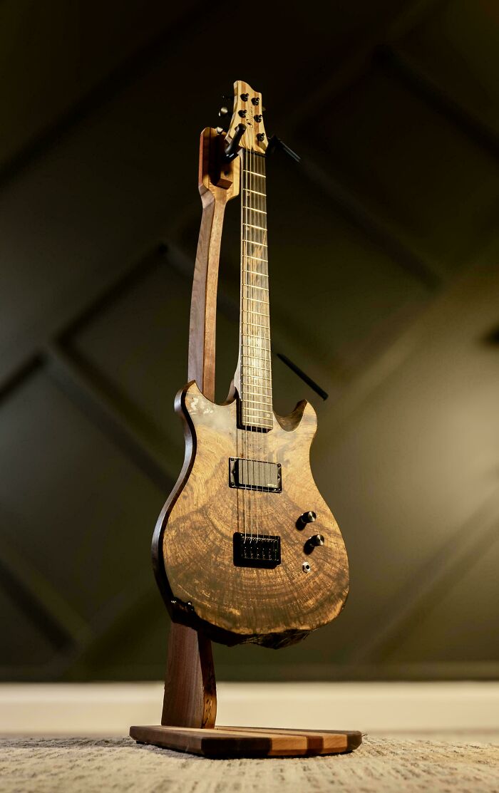 Woodworking project: an intricately designed wooden guitar standing on a custom wooden stand.