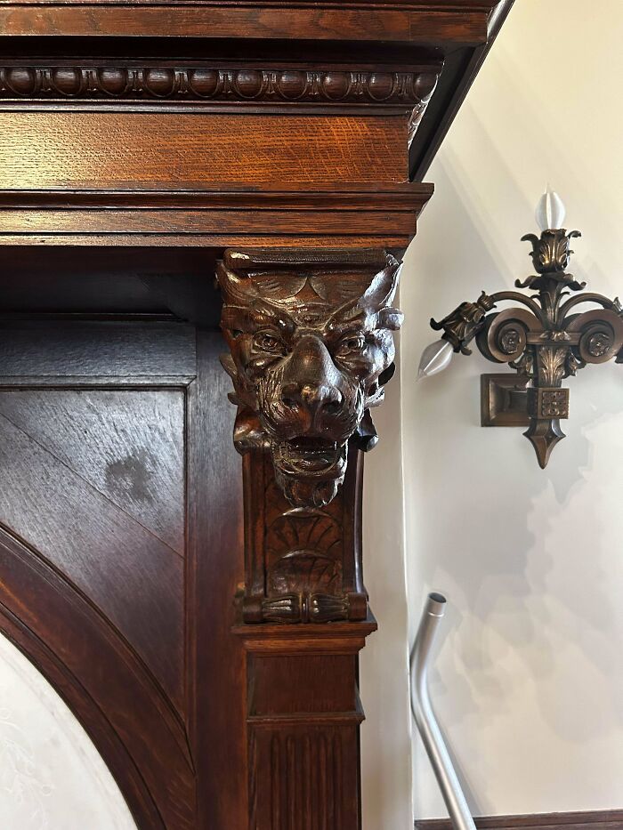 Ornate wood carving of a lion's head on a fireplace, showcasing impressive woodworking craftsmanship.