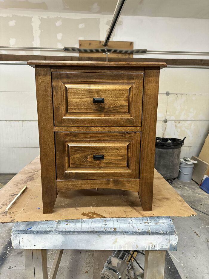 Woodworking project featuring a handcrafted wooden drawer unit with a polished finish, showcased in a workshop setting.