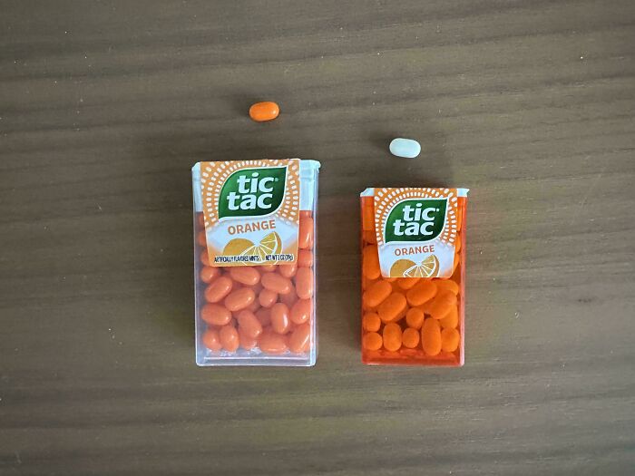 Mildly interesting: Two Tic Tac boxes, one with an orange and a white Tic Tac on a table.