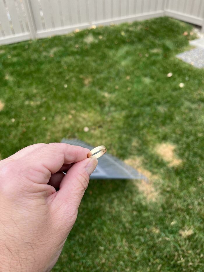 Hand holding a ring near a patch of grass, creating a rainbow effect; mildly interesting moment captured outdoors.