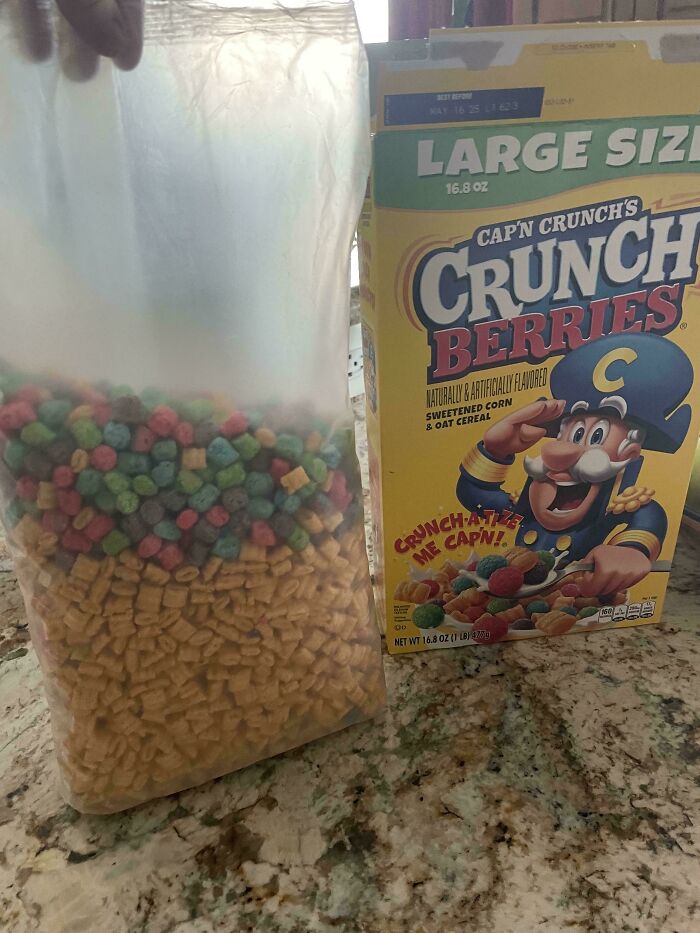 Large cereal box of Cap'n Crunch Berries with unevenly mixed contents poured into a clear bag on a marble countertop.