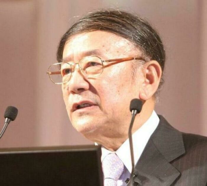 Man with a comb-over hairstyle speaking at a podium; example of a hair mishap discussed online.