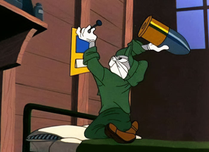 Bugs Bunny, dressed in green, prepares to load a large shell into a weapon inside a wooden cabin, signaling action. The scene conveys focus and determination.