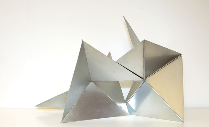 A geometric metal sculpture by the famous artist Lygia Clark, composed of interconnected triangular shapes, with sharp angles and a metallic finish.