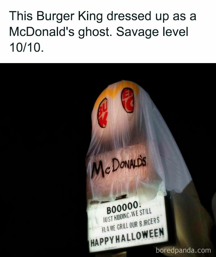 A Halloween meme featuring a Burger King sign covered with a ghostly sheet, labeled "McDonald's" to imitate McDonald's as a ghost. The caption above reads, "This Burger King dressed up as a McDonald's ghost. Savage level 10/10." The sign humorously says, "BOOOOO! Just kidding, we still flame grill our burgers. Happy Halloween," mocking their competitor.