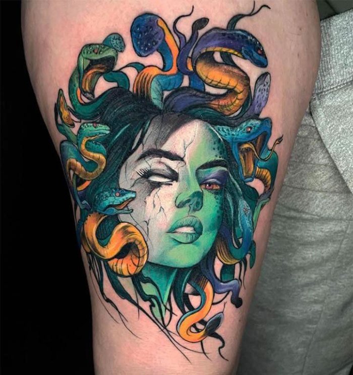 A colorful Medusa tattoo featuring a woman's face with greenish skin, cracked markings, and vibrant snakes entwined in her hair, showing intricate detail.