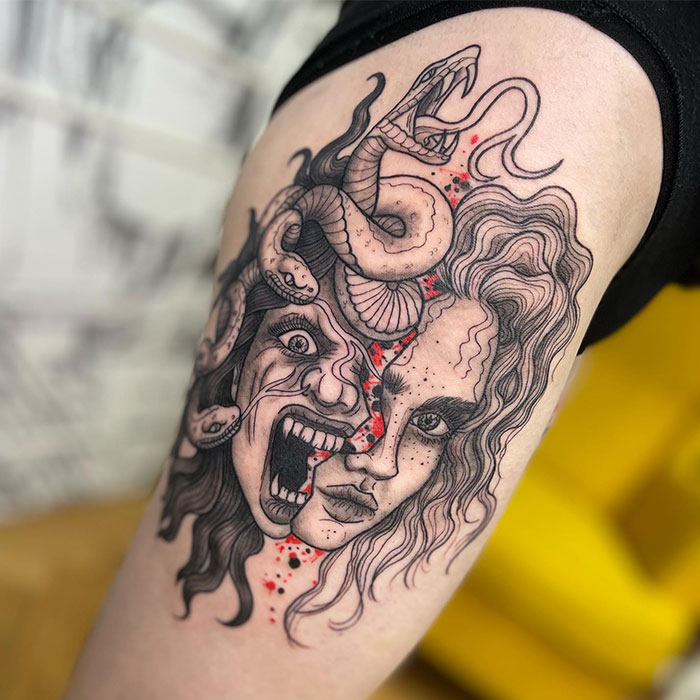  A detailed Medusa tattoo featuring a split face design, with one side showing a calm expression and the other a screaming face, entwined with snakes and accented by splashes of red.