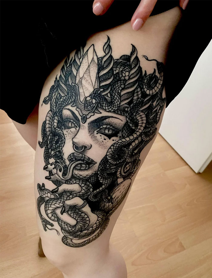 A black and grey Medusa tattoo featuring a woman's face adorned with detailed snakes and a large crystal-like crown, creating a mystical and intense design.