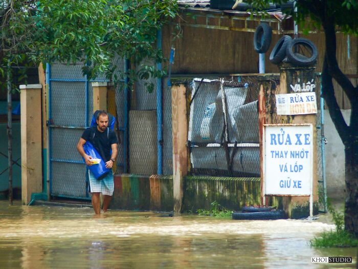 Tourists Wade Through Water As They Walk On The Sidewalk On A Flooded Day In Hoi An