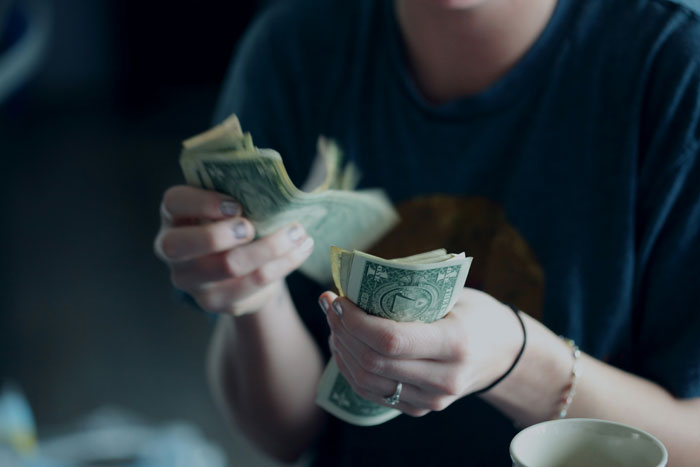 Young adult counting money at a table, illustrating inheritance issues and family manipulation.