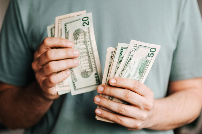 Person counting money, illustrating homeowner debt payment scenario.