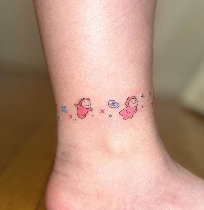 "A small tattoo idea with cute pink cartoon characters and colorful shapes forming a playful anklet design around the ankle."