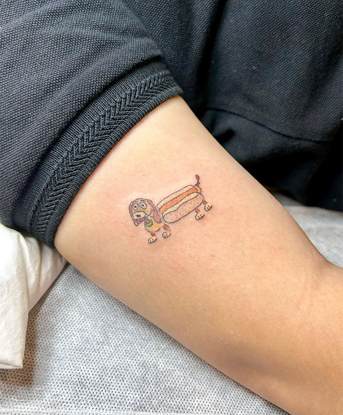 "A small tattoo idea featuring a whimsical illustration of a dachshund designed as a hot dog on the upper arm, adding a playful and humorous touch."