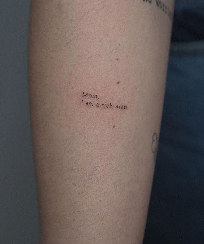 "A small tattoo idea featuring the quote 'Mom, I am a rich man' in a simple font on the forearm, adding a personal and empowering touch."