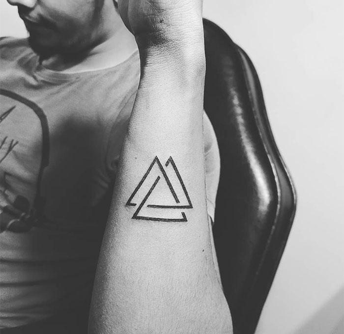  "A small tattoo idea featuring two overlapping minimalist triangles on the forearm, creating a modern and geometric design."