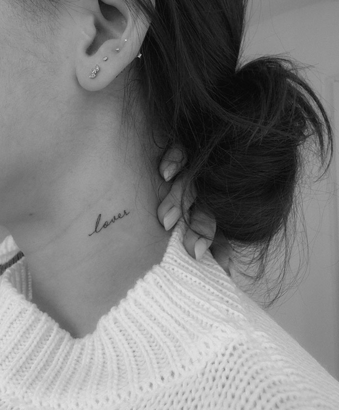 "A small tattoo idea featuring the word 'lover' in delicate cursive script on the side of the neck, adding a subtle and romantic touch."