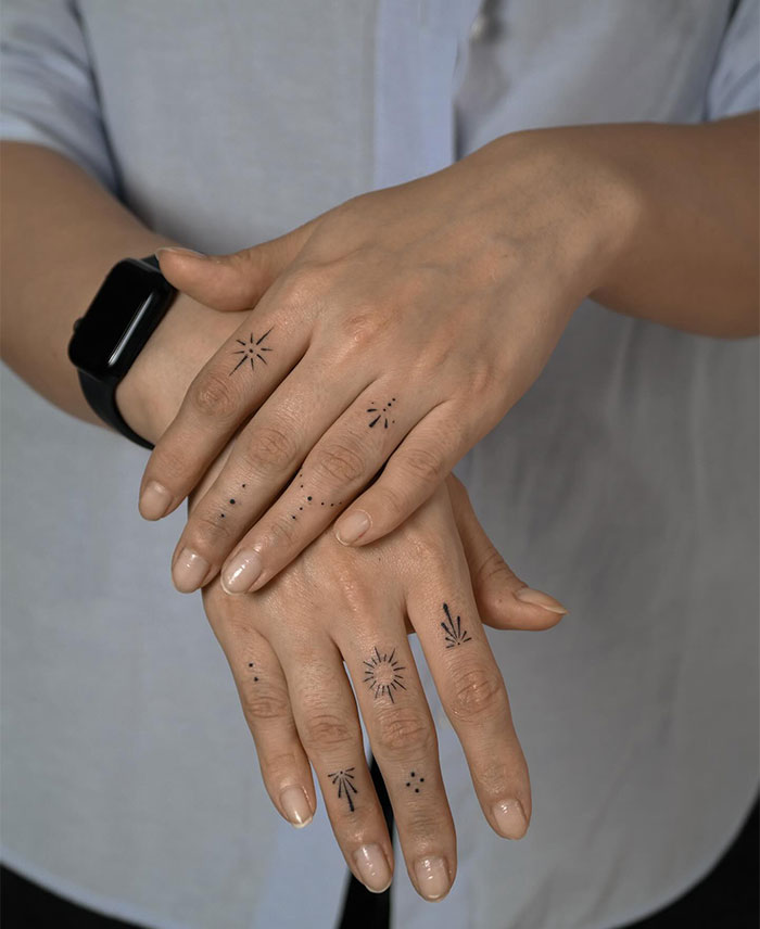 "A small tattoo idea featuring minimalist celestial symbols and dot patterns on the fingers and hands, creating an elegant, decorative look."