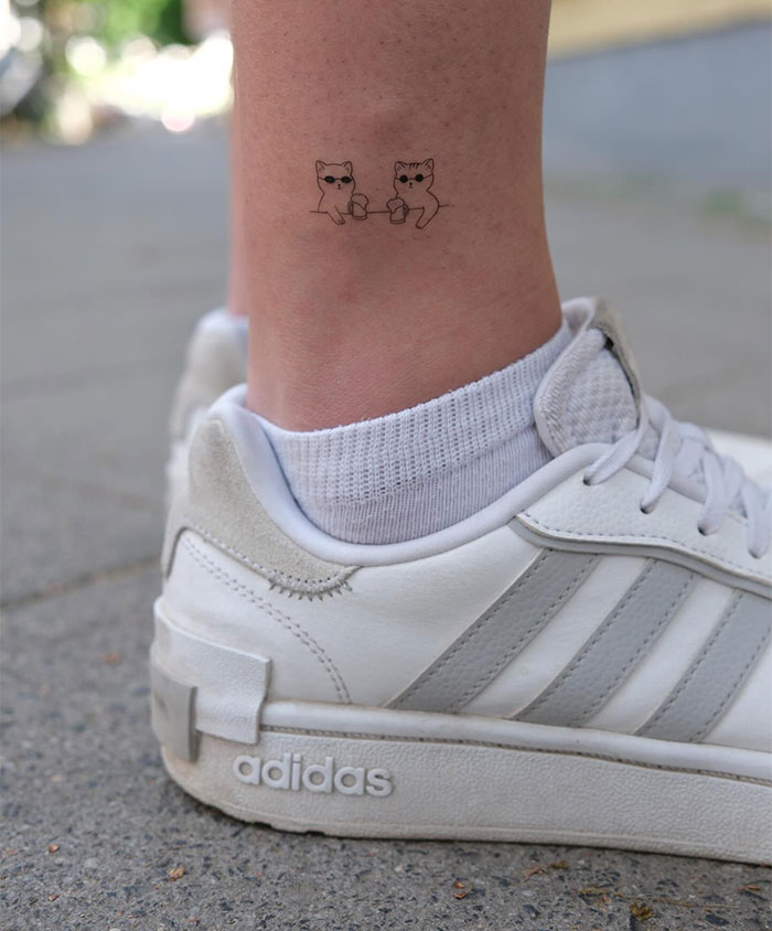 "A small tattoo idea featuring two cute cats clinking mugs on the ankle, adding a playful and charming touch."