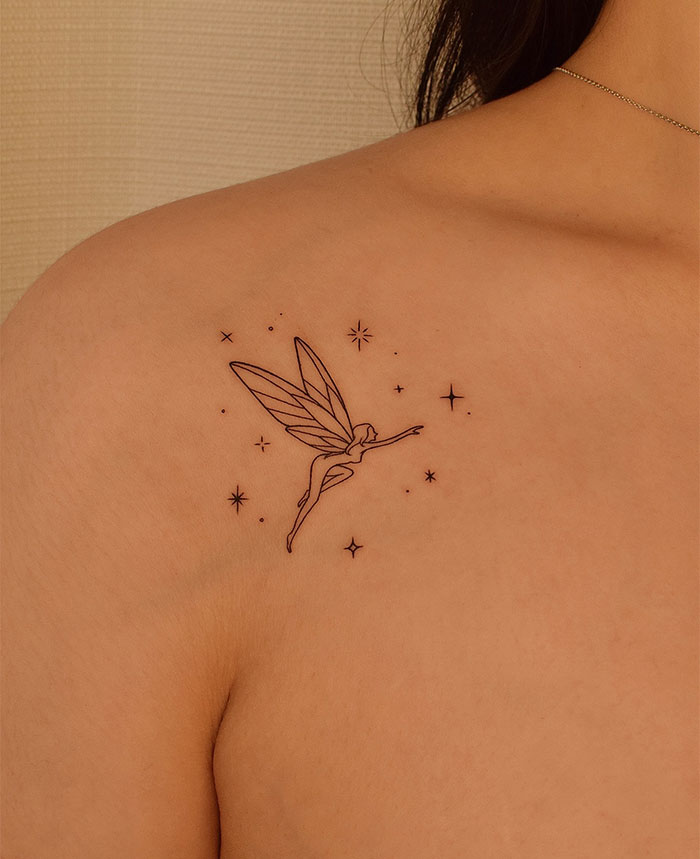 "A small tattoo idea of a delicate fairy surrounded by stars on the upper back, creating a magical and whimsical effect."