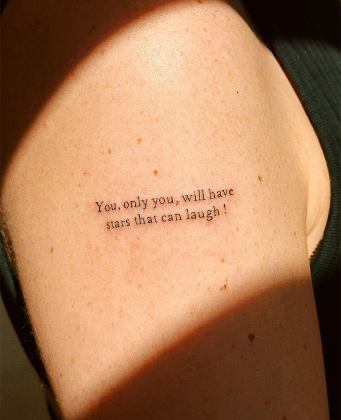 "A small tattoo idea featuring the quote 'You, only you, will have stars that can laugh!' on the upper arm in simple, elegant font."