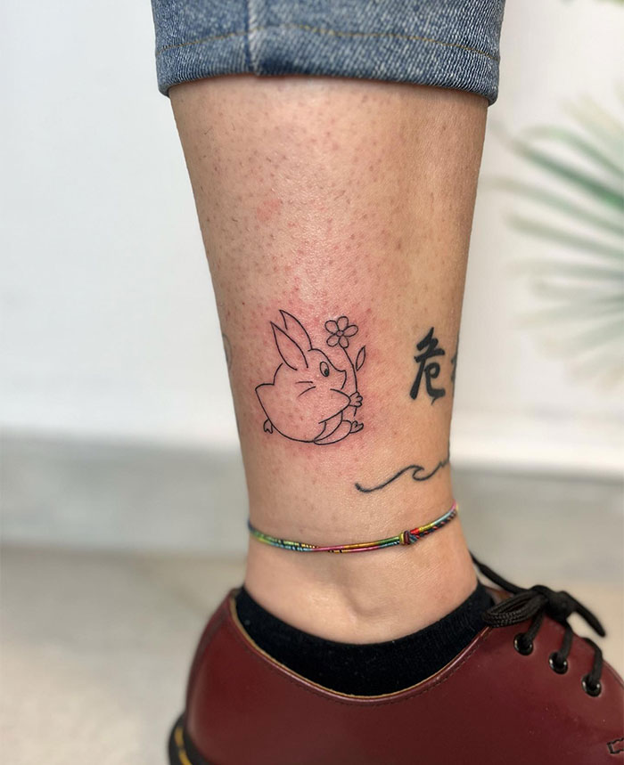 "A small tattoo idea featuring a cute bunny holding a flower, placed on the lower leg, perfect for adding charm and simplicity."