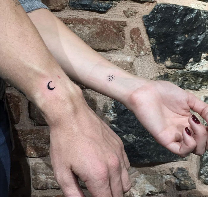 "A small tattoo idea for couples featuring complementary designs of a crescent moon on one wrist and a sun on the other, symbolizing balance."