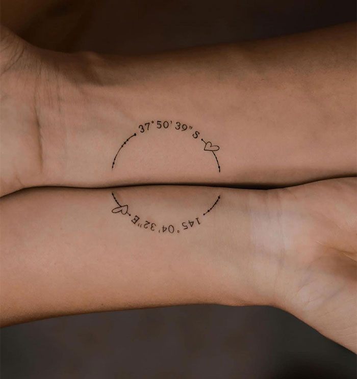 "A small tattoo idea featuring matching wrist tattoos with coordinates in a semi-circle, decorated with tiny heart symbols, representing a meaningful location."