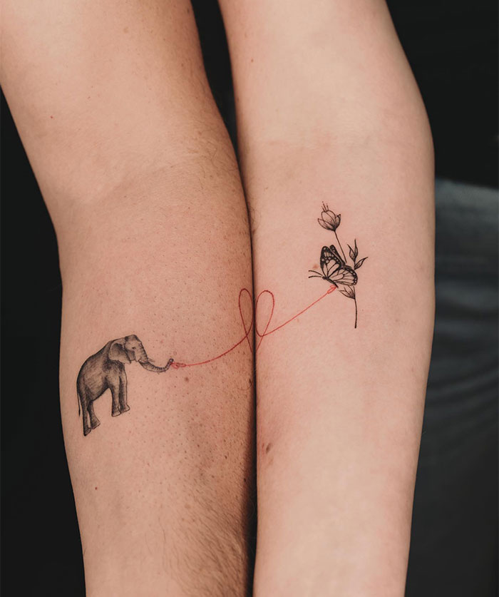 "A small tattoo idea featuring an elephant and a butterfly connected by a red string, symbolizing connection and harmony between two people."